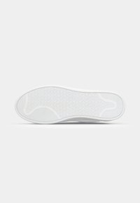 Semelle de chaussure blanche en caoutchouc texturé, avec un bord lisse et une surface à motifs pour une meilleure adhérence.