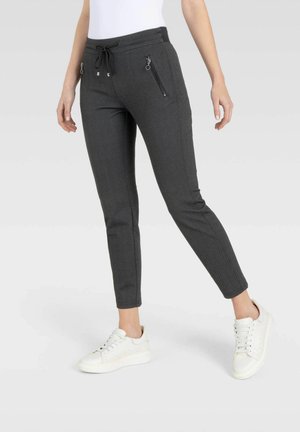 Dunkelgraue Hosen mit Fischgradmuster, elastischem Bund, seitlichen Reißverschlusstaschen und tapered Beinen, kombiniert mit weißen Sneakern.