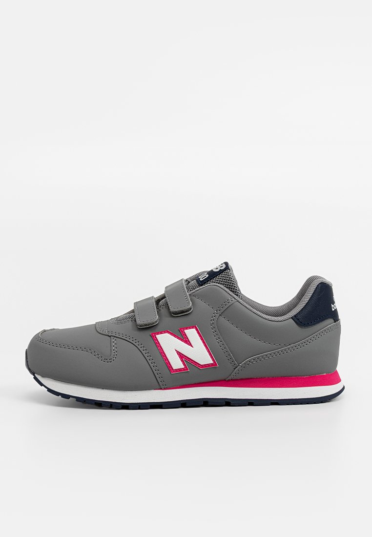 Las zapatillas sintéticas grises presentan una correa de Velcro, acentos en blanco y rosa, un panel texturizado en gris y una suela resistente con un taco azul.