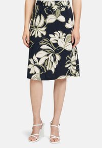 Blumendruckrock mit dunkelblauem Hintergrund, der große weiße und hellgrüne Blätter zeigt. Er hat einen elastischen Taillenbund für zusätzlichen Komfort.