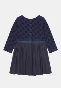 Vestido de marine con mangas largas, patrón de estrellas en el cuerpo, falda recogida y una cinturilla brillante con cierre de botón en la parte trasera.