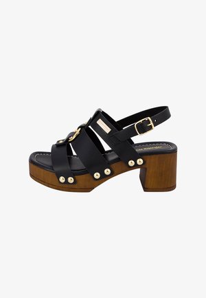 Sandale en cuir noir avec talon bloc, base en bois et ferrures dorées. Comprend un design à brides et des clous décoratifs sur le côté.