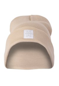 Beige ribbed knit beanie with a folded cuff and a square white tag featuring a subtle logo on the front. Soft texture.