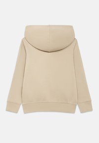 Μπεζ φούτερ με απαλό ύφασμα, μεγάλο στρογγυλεμένο κουκούλι, ριμπ μανσέτες και άνετη εφαρμογή. Η πλάτη είναι ομαλή χωρίς εμφανή λογότυπα ή σχέδια.