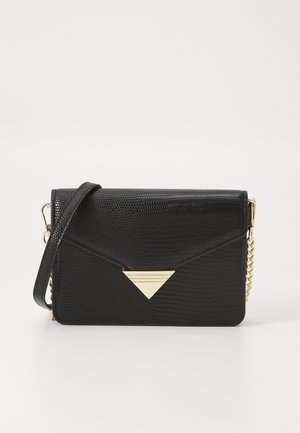 Sac bandoulière en similicuir noir avec extérieur texturé, orné d’un accessoire triangulaire doré, et une sangle unique en chaîne.