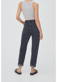 Jean en denim gris foncé taille haute avec une coupe droite et des revers roulés, doté de deux poches arrière et de détails de couture subtils.