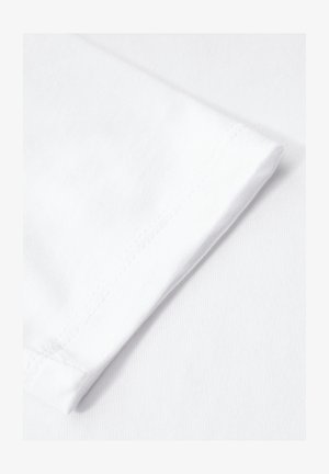 Tela de algodón blanco con un dobladillo de manga doblado. La textura es suave con un ligero brillo. Las costuras son visibles a lo largo del borde.