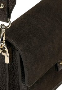 Close-up of a dark brown leather and suede handbag with a gold metal clasp and a textured surface.