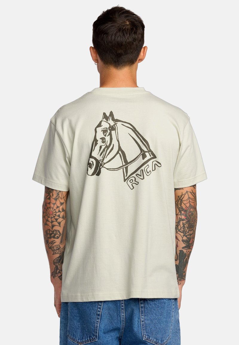 T-shirt di colore beige chiaro in cotone, con un'illustrazione di un cavallo nero sul retro e il logo "RVCA" sotto. Maniche corte, vestibilità rilassata.