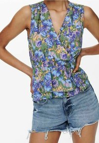 Ärmelloses Floral-Top in Grün-, Lila- und Blautönen mit Wickeldesign und gerafftem Saum, kombiniert mit zerrissenen Jeansshorts.