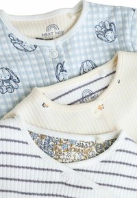 Drie baby tops: één lichtblauw geruit met konijnenprint, één roomkleurig met bloemenvoering, en één wit gestreept met blauwe accenten.