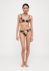 Bikini noir avec motif floral en orange et vert. Haut triangle avec fines bretelles, bas taille basse assortis. Texture de tissu lisse.