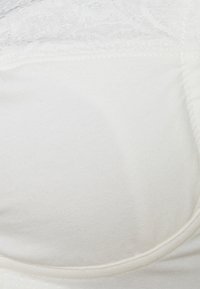 Sutiã branco com uma base de tecido suave e detalhes em renda na parte superior. O design inclui suporte com aros e copas arredondadas.