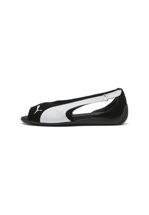 Zapato plano tipo slingback en blanco y negro con puntera abierta, recortes laterales y logo de Puma en la parte frontal.
