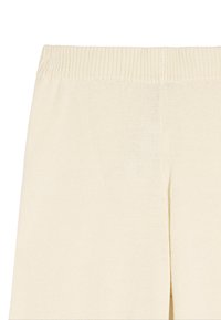 Dzianinowe spodnie w kolorze kremowym z prążkowanym pasem i bocznymi rozcięciami. Tkanina ma teksturowane wykończenie z luźnym, przewiewnym splotem.