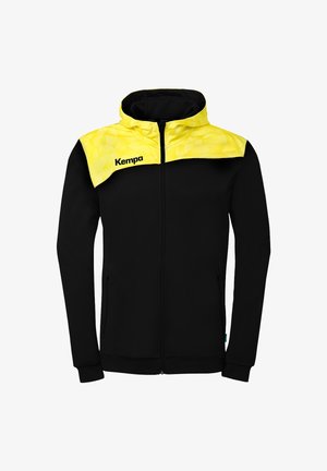 Black zip-up hoodie with yellow geometric patterned yoke and hood, featuring "Kempa" logo on the left chest.