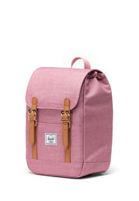 Ružový textilný batoh s hnedými koženými popruhmi a prackami, s preklopným vekom a prednou kapsou, na ktorej je biely značkový štítok.