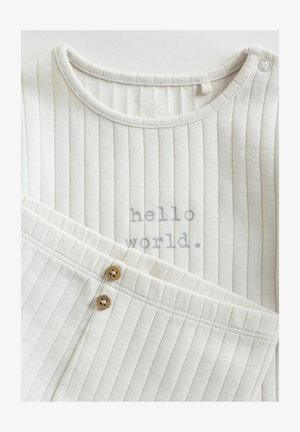 Hvid ribstrikket bomuldstøj med rund halsudskæring, med teksten "hello world" i gråt og to træknapper på bukserne.