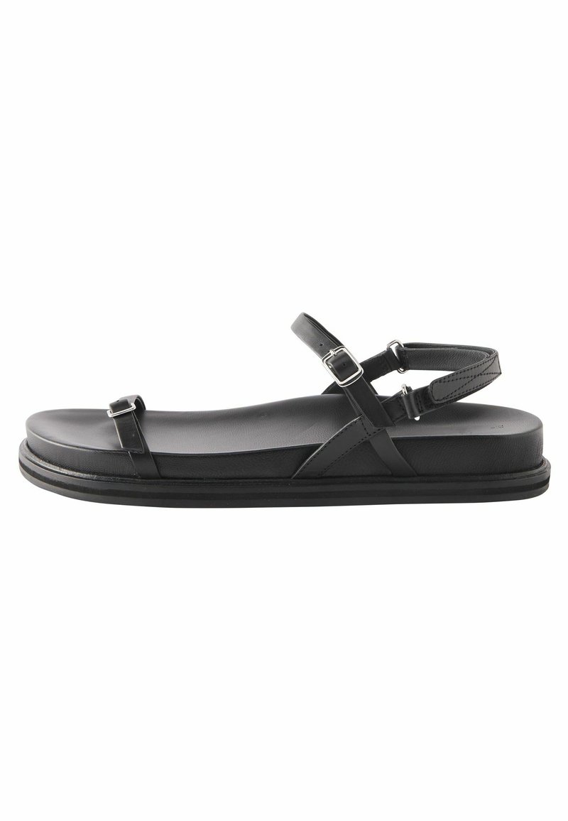 Svarta platta sandaler med en minimalistisk design, som har en stadig sula, två justerbara spännen och en slät matt yta.
