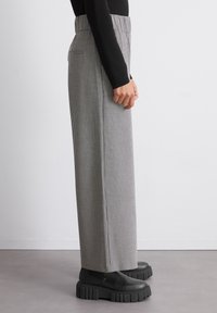 Schwarz-weiße karierte weite Hosen mit hoher Taille, aus strukturiertem Stoff, kombiniert mit klobigen schwarzen Plateaustiefeln.