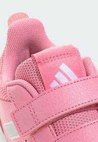 Różowy trampek z teksturowaną, siateczkową wyściółką wewnątrz i gładką, skórzaną powierzchnią na zewnątrz. Pasek i branding w kontrastowej bieli dla lepszej widoczności.