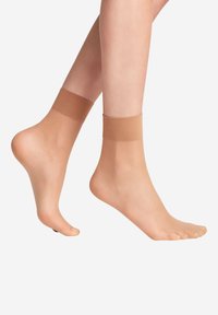 Hautfarbene Knöchelsocken mit glatter Textur und weichem elastischen Bund, entworfen dafür, eng um den Knöchel zu sitzen, ohne die Zehen zu bedecken.