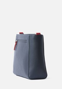 Navy leren tote bag met een textuurafwerking. Rode korte handvatten en een ritszak aan de achterkant. Strakke vorm met een platte bodem.