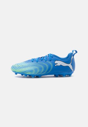 Chaussure de football bleue avec un motif tourbillonnant vert et un logo blanc Puma sur le côté, avec des crampons sous la semelle pour l'adhérence sur l'herbe.