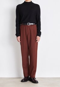 Schwarzer Rollkragenpullover, lockere braune Hose, schwarzer Gürtel, glänzende dunkle Schuhe. Sanfte Texturen, minimalistisches Design, einfache Farbpalette.