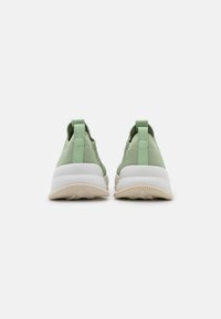 Paire de baskets vert clair à enfiler avec semelles blanches, vues de dos sur fond blanc.