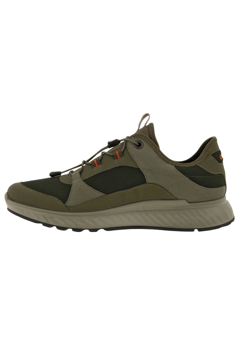 Scarpa sportiva in verde oliva e nero, caratterizzata da una combinazione di materiali in rete e camoscio, lacci elastici e suola in gomma testurizzata.