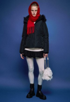 Giacca imbottita nera con cappuccio in pelliccia, sciarpa rossa, maglione bianco, gonna nera, collant bianchi e stivali da combattimento neri. Tiene in mano una borsa bianca e soffice.