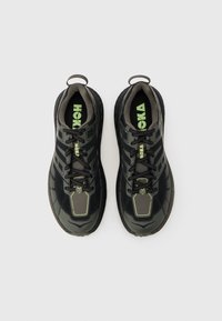 Ζευγάρι μαύρα και σκουρόγιαλα παπούτσια τρεξίματος Hoka με μαύρα κορδόνια και λογότυπο σε νέον πράσινο, από ψηλά σε φόντο ανοιχτού γκρι.