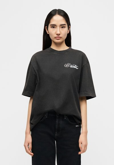 Μαύρο υπερμεγέθες μπλουζάκι από βαμβάκι, με λευκό λογότυπο "Off-White" στο στήθος, συνδυασμένο με μαύρο τζιν. Απλός, άνετος σχεδιασμός.