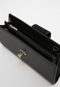 Black synthetic leather wallet with a gold clasp, zippered section, and internal card slots. Features a smooth surface and clean lines.