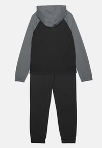 Tuta nera con cappuccio e maniche grigie. La parte superiore ha una vestibilità regolare, mentre i pantaloni hanno un design affusolato con polsini elasticizzati.