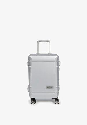 Maleta rígida plateada con cuatro ruedas y asa telescópica, etiquetada con el logo de la marca Eastpak en el panel frontal.