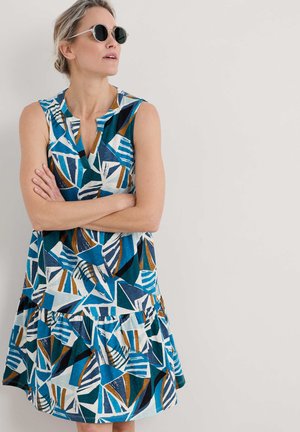 A sleeveless dress with a tiered skirt, featuring a bold geometric pattern in teal, blue, white, and brown, made from lightweight fabric.