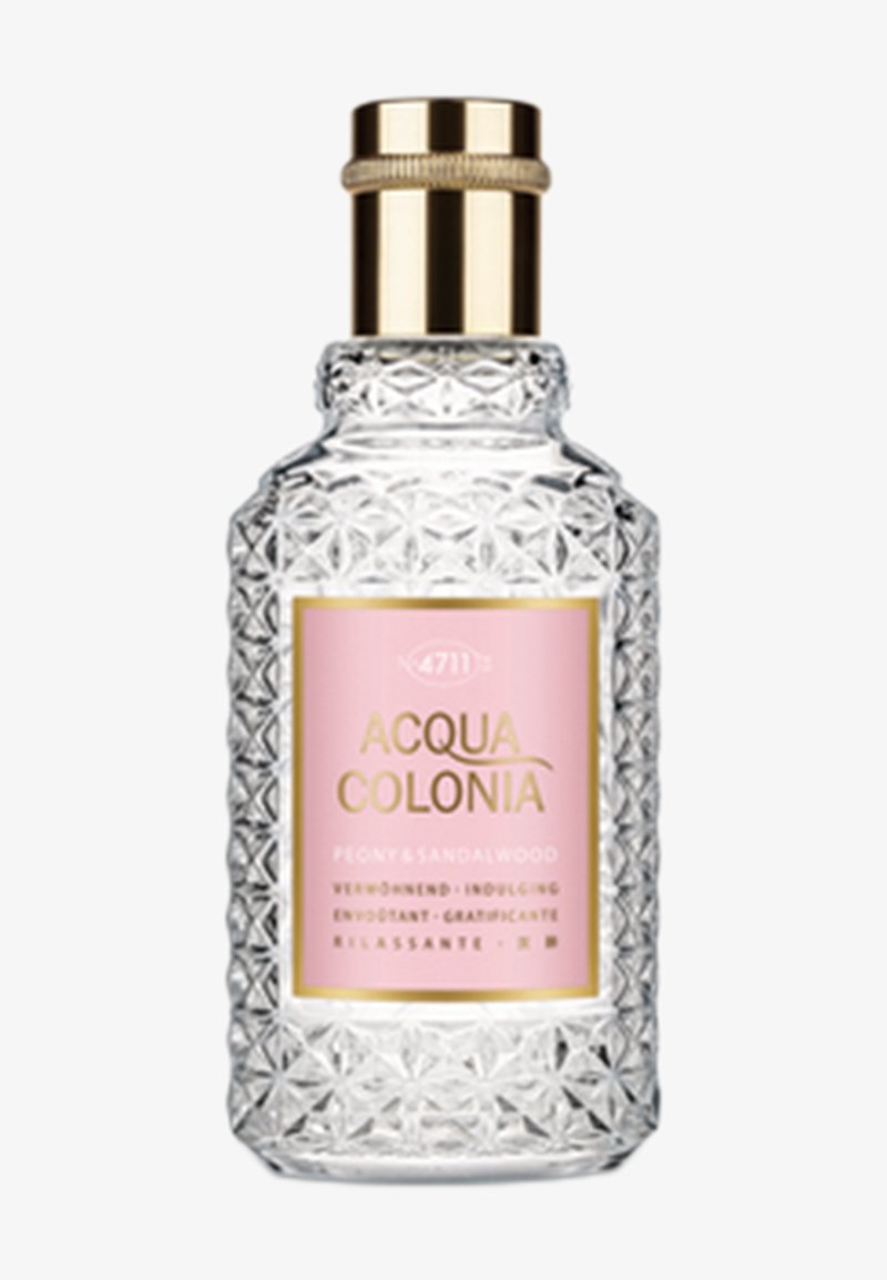 Flacon de parfum en verre taillé avec un motif géométrique et une étiquette rose indiquant Acqua Colonia Menthe & Bois de Santal. Bouchon doré sur le dessus.