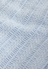 Hele sinine kangas tekstuursete, kokku kogutud ja kortssabade horisontaalsete triipudega, mis loovad pehme, mustrilise pinna.