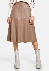 Brun faux læder midi nederdel med et tekstureret diamantmønster, svajet design, sidelommer og en glat finish, parret med lysegrå støvler.