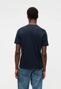 Μπλε ναυτικό βαμβακερό T-shirt με κοντά μανίκια και στρογγυλή λαιμόκοψη. Η πίσω πλευρά είναι απλή, χωρίς ορατά λογότυπα ή σχέδια.