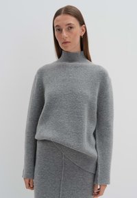 Grauer Wollpullover mit Rollkragen und langen Ärmeln, mit einem leicht asymmetrischen Saum, einem weichen Material und minimalistischem Design.