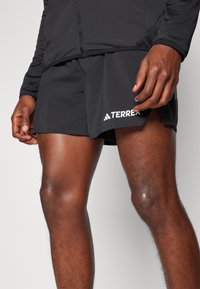Black athletic shorts with a sleek design, featuring the "TERREX" logo in white. Lightweight fabric and a comfortable fit.