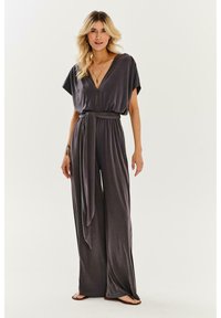 Sivý overal s širokými nohavicami, krátkymi rukávmi, hlbokým V-výstrihom a opaskom v páse. Hladká tkanina s jemnou textúrou.