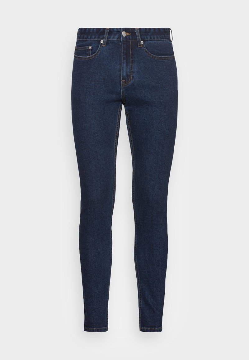 Ciemnoniebieskie jeansy slim fit z pięcioma kieszeniami, zapięciem na guziki i widocznym przeszyciem na gładkim tle.