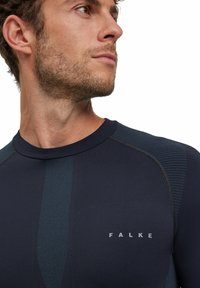T-shirt de sport marine en tissu lisse et texturé, avec un logo bien visible et un design à accents verticaux sur le devant.