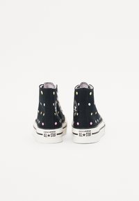 Černé vysoké tenisky Converse s barevnými puntíky, bílé gumové podrážky a logo "Converse All Star" na patě.