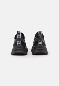 Black athletic sneakers featuring a textured upper, padded ankle support, and a bold striped pull tab at the heel. Thick rubber outsole.
