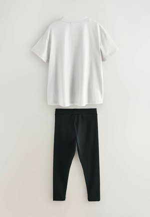 Bílé tričko s krátkým rukávem a kulatým výstřihem vystavené nad černými legínami. Oba kusy oblečení mají hladkou, jemnou texturu.